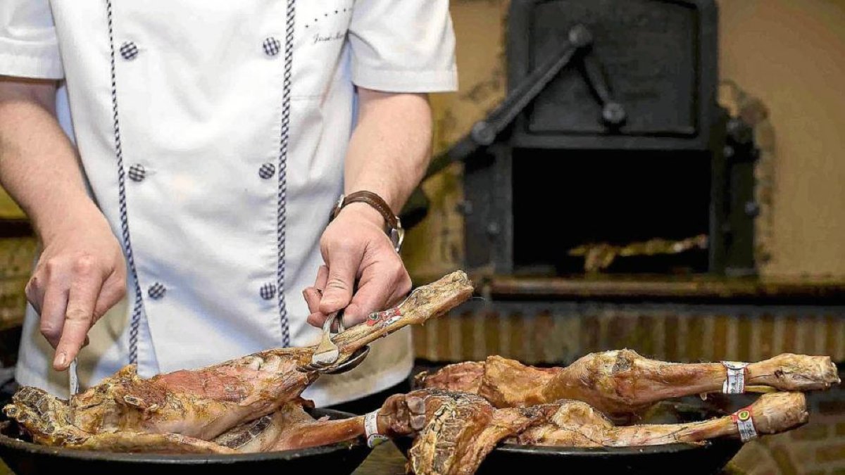 Un asador trincha el lechazo durante la elaboración del alimento en horno de leña.- E. M.