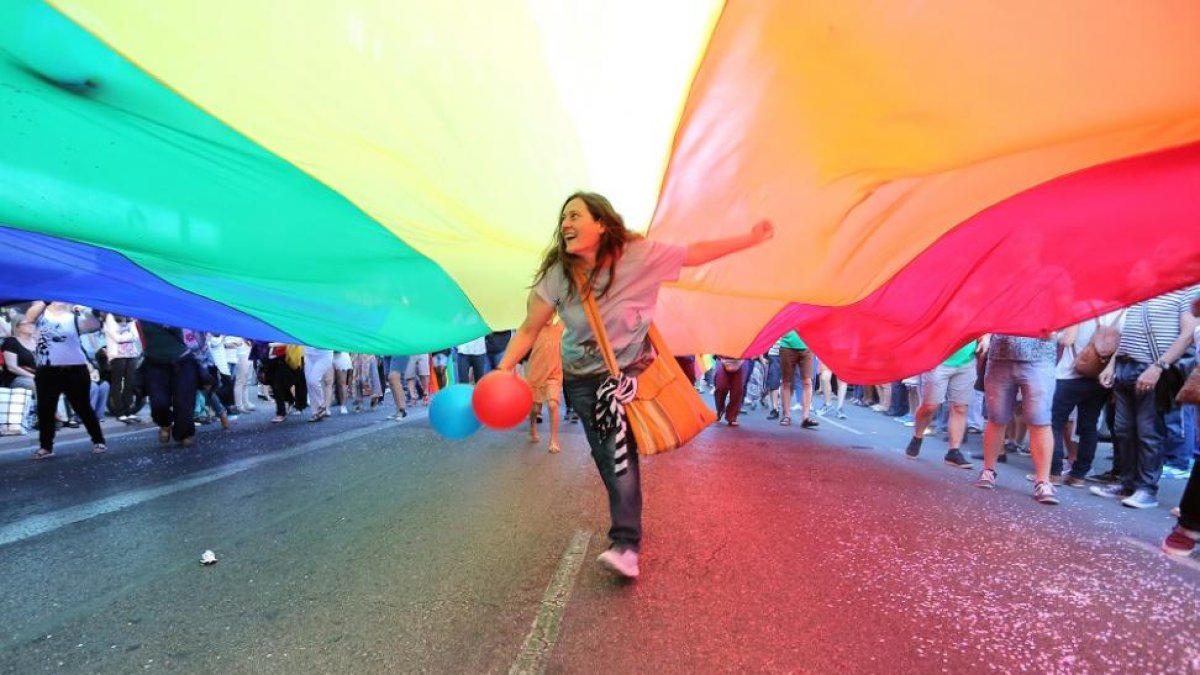 Una joven corre por debajo de la bandera arcoíris en una manifestación LGTBI.-EL MUNDO