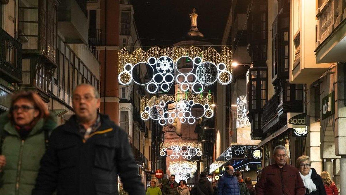 Transeúntes por la calle Regalado bajo la iluminación navideña.-J.M. LOSTAU