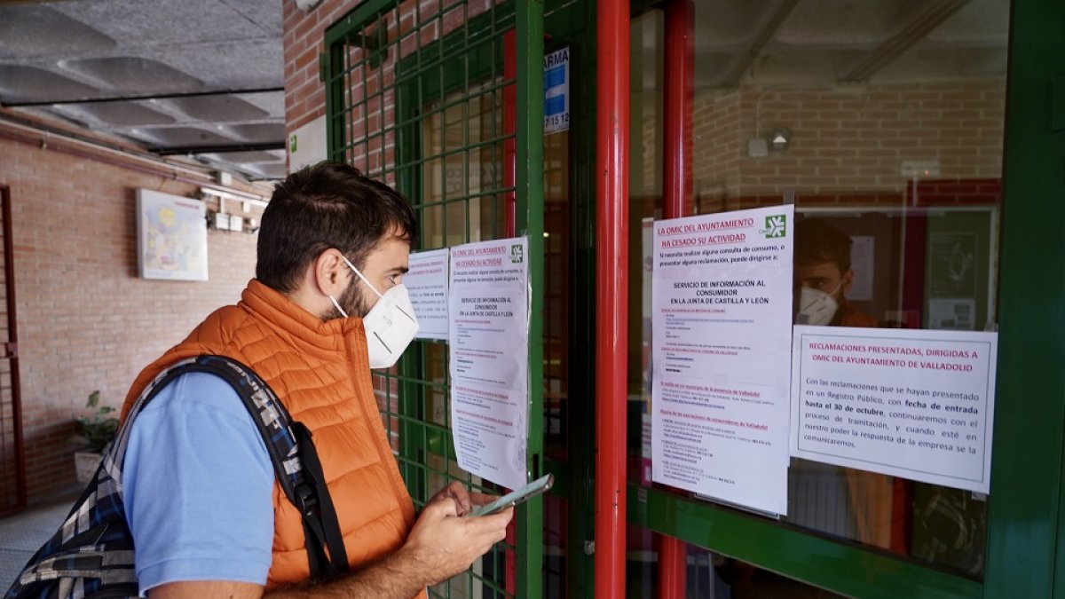 Un usuario consulta los números de teléfono proporcionados por el centro por el cierre de la Oficina de Municipal de Consumo de Valladolid.- ICAL
