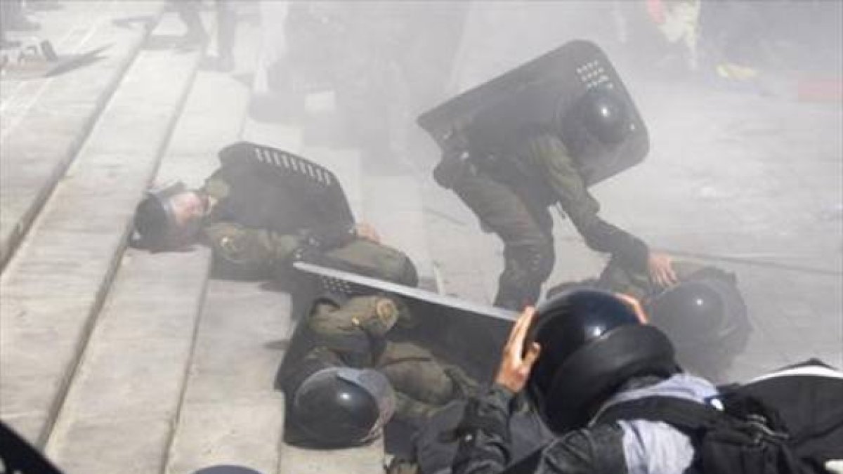 Agentes ayudan a colegas heridos durante los disturbios de ayer en Kiev.-AFP / YURIY KIRNICHNY