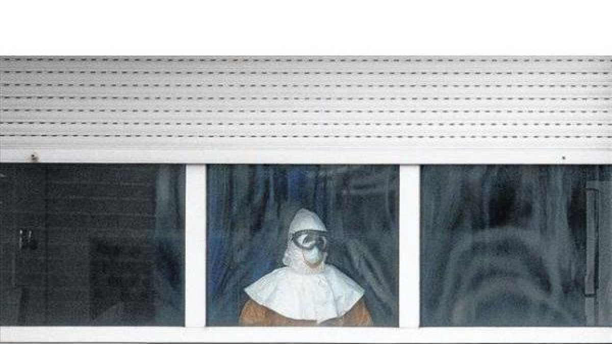 Un sanitario equipado con el traje de protección mira hacia el exterior desde la sexta planta del Carlos III.-Foto: PAUL HANNA / REUTERS