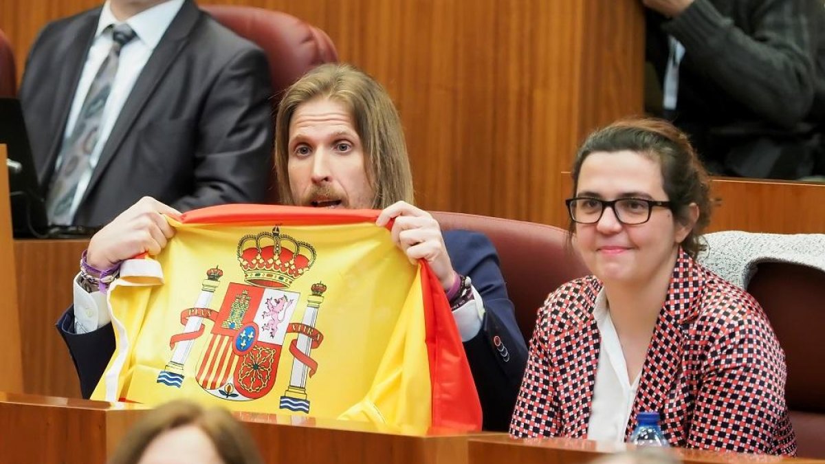 El portavoz de Podemos, Pablo Fernández, exhibe desde su escaño una bandera española durante la réplica de Herrera. .-M. A. SANTOS