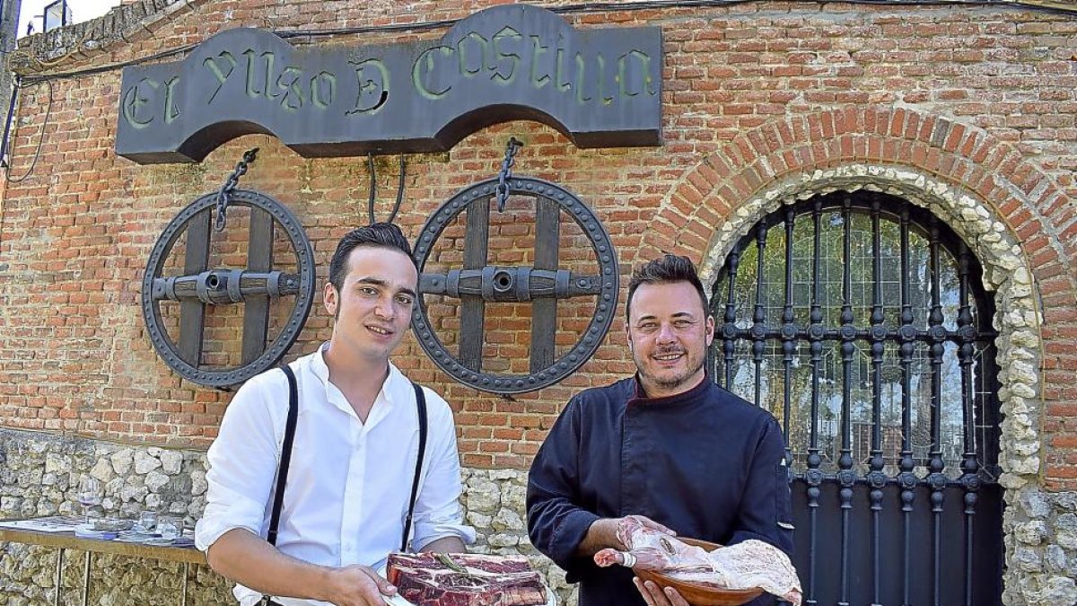 Rodrigo y Alfonso (con un cuarto de lechazo en cazuela de barro) a la entrada del mítico restaurante de Boecillo, que ambos regentan desde hace medio año.-ARGICOMUNICACIÓN