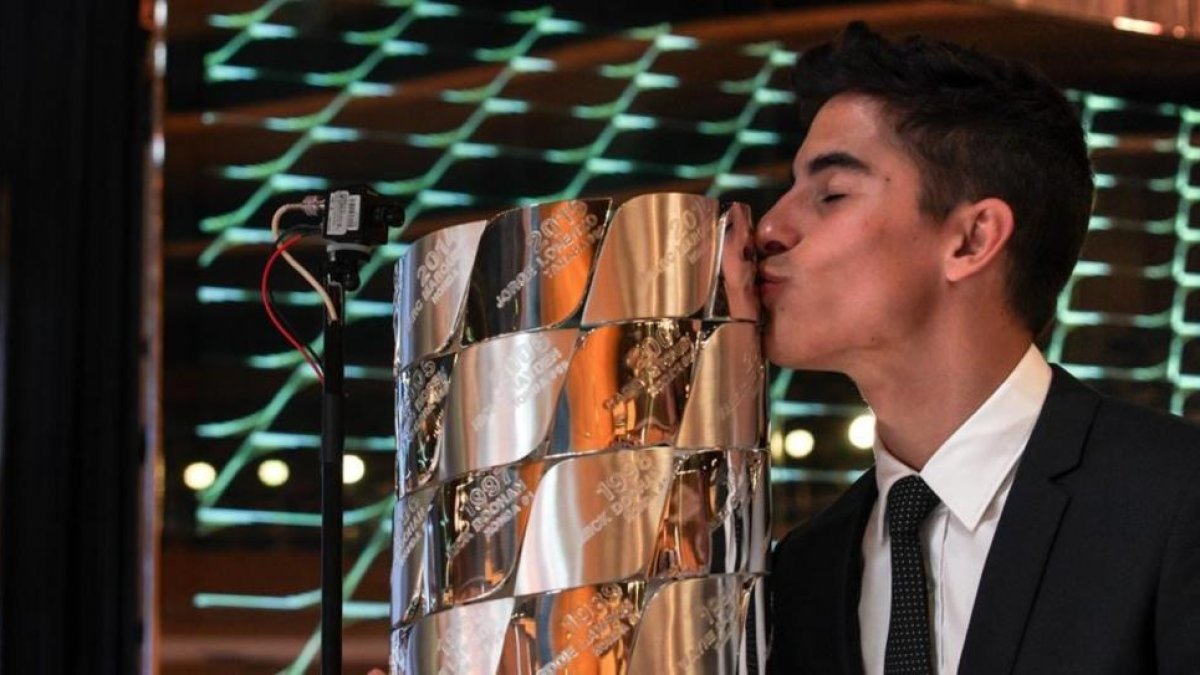 Marc Márquez besa el trofeo de plata maciza en el que están inscritos los nombres de todos los campeones de Moto GP.-ALEJANDRO CERESUELA