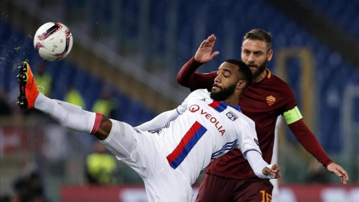 Lacazette, disputa un balón con De Rossi durante un encuentro entre el Lyon y la Roma de Liga Europa.-EFE / ANGELO CARCON