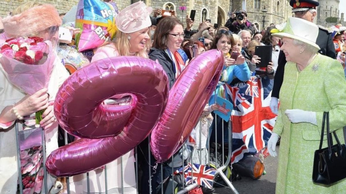 La reina Isabel saluda este jueves al público que la ha esperado junto al castillo de Windsor para felicitarla por su 90º aniversario.-AFP / JOHN STILLWELL