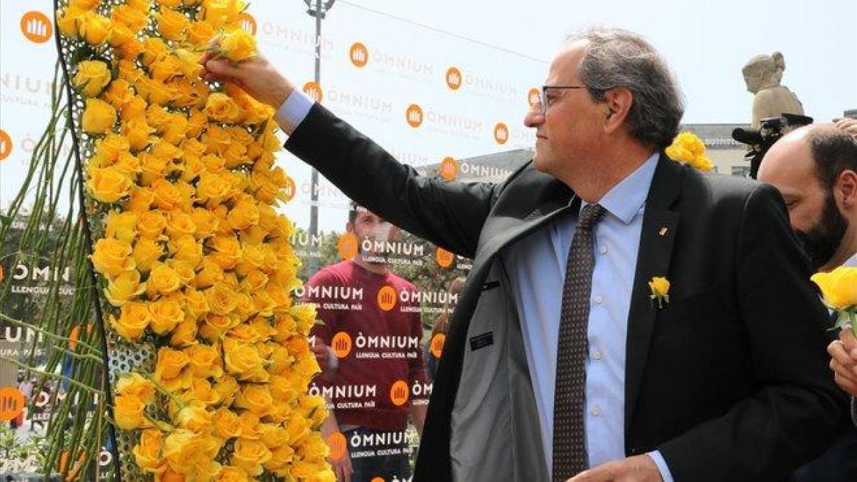 El presidente Quim Torra coloca una rosa amarilla en el mural de Òmnium.-BLANCA BLAY (ACN)