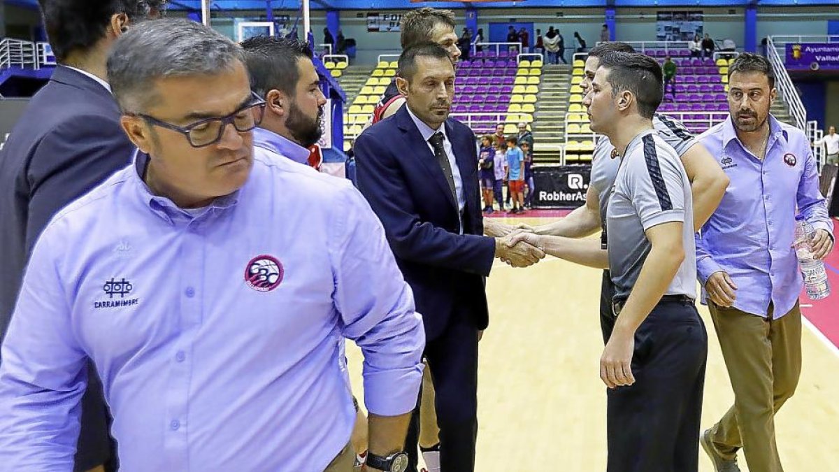 Los árbitros Aranzana y Gómez saludan a Lezcano, técnico del Breogán, mientras Paco se marcha enfadado.-J. M. LOSTAU