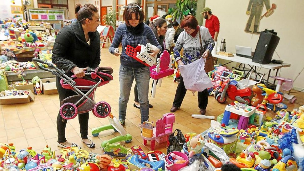Varios asistentes recogen juguetes en el ‘hall’ del Centro Cívico de las Delicias.-J.M. Lostau