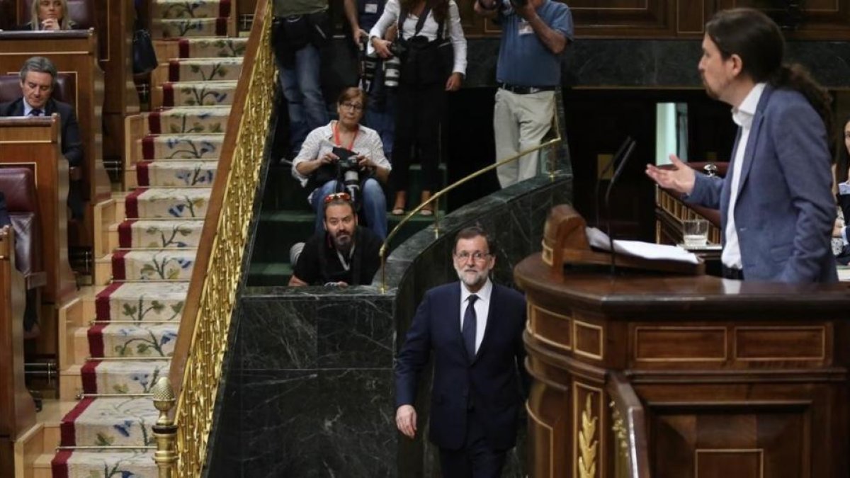 Mariano Rajoy vuelve a su escaño tras unos minutos fuera del hemiciclo mientras Pablo Iglesias habla en la tribuna.-JUAN MANUEL PRATS