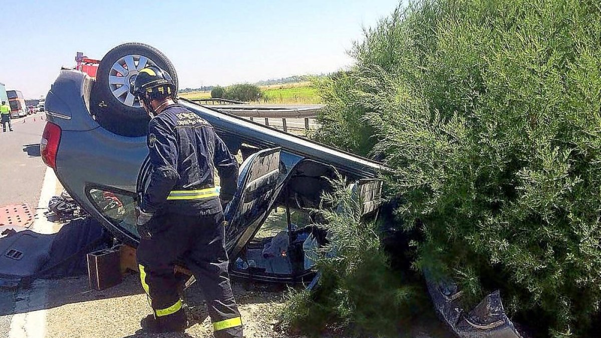 Un bombero, junto al vehículo que volcó a la altura de Geria.-ICAL