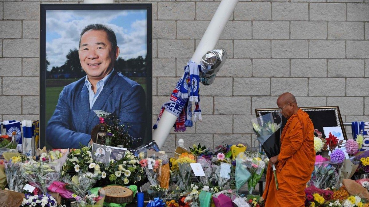 Un monje budista deja unas flores junto a la fotografía del empresario, a las afueras del estadio del Leicester.-afp