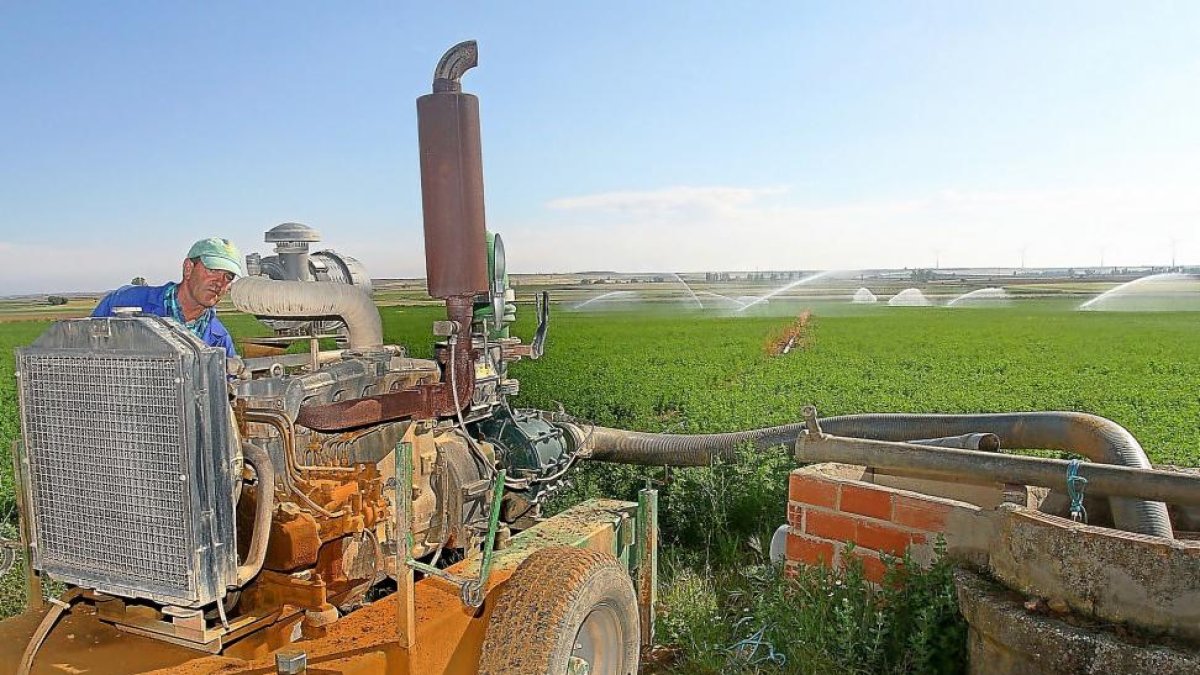 Un agricultor junto a un pozo regando su parcela en la provincia de Palencia.-BRÁGIMO