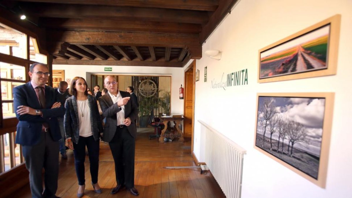 El presidente de la Diputación de Valladolid, Jesús Julio Carnero, recorre la exposición fotográfica 'Naturaleza Infinita' tras la presentación de la oferta de la institución en la Feria Intur. En la imagen, observan las imágenes de Luis Laforga-Miriam Chacón / ICAL