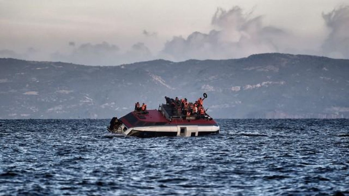 Refugiados piden socorro desde una barcaza que se hunde ante la isla de Lesbos, este viernes.-ARIS MESSINIS / AFP