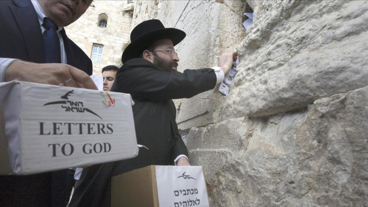 Un rabino deja cartas destinadas a Dios en el Muro de las Lamentaciones en Jerusalén.-/ AFP / MENAHEM KAHANA