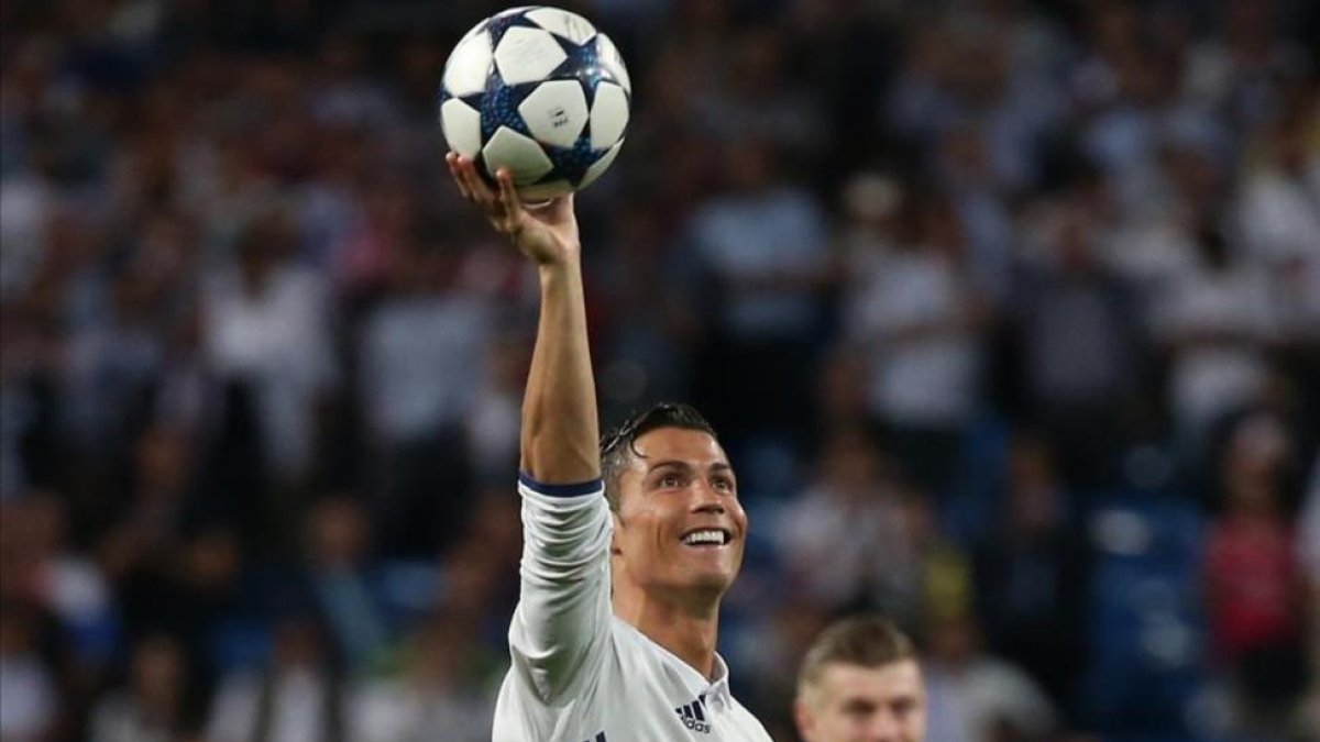 Cristiano Ronaldo luce el balón que se llevó como recompensa a los tres goles anotados ante el Bayern.-SERGIO PÉREZ