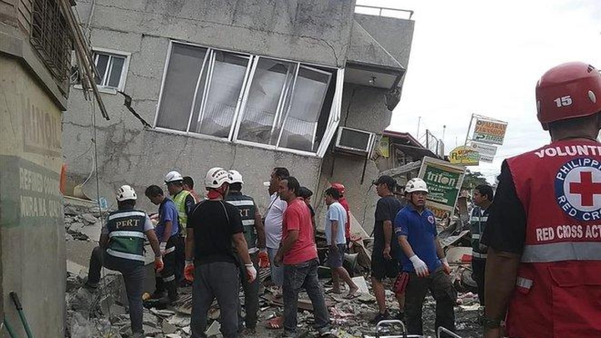 Miembros del servicio de rescate inspeccionan un edificio en Padada Davao afectado por el terremoto en busca de víctimas.-EFE