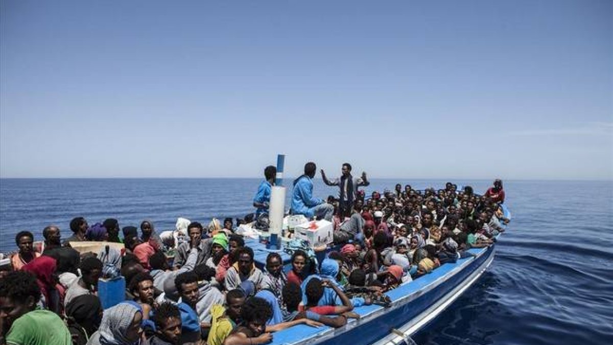 Inmigrantes a bordo de una patera intentando cruzar el Mediterráneo son rescatados por la Marina Militar italiana.-Foto: AFP / JASON FLORIO