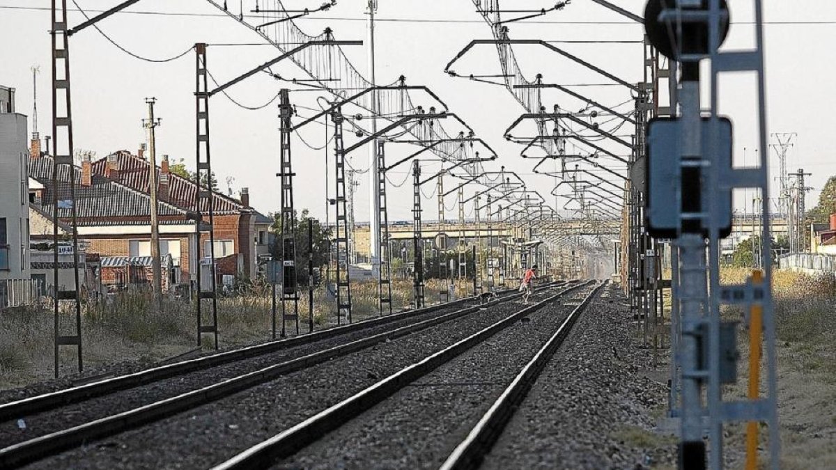 Un joven atraviesa las vías del tren a su paso por la ciudad por un lugar no autorizado.-PABLO REQUEJO