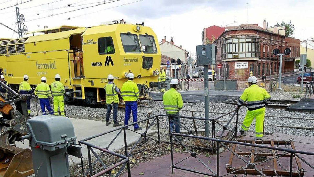 Operarios junto a la máquina niveladora de vías, ayer, en el paso a nivel de Pilarica temporalmente cerrado-J.M. Lostau