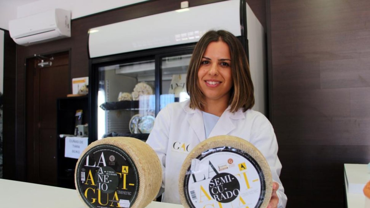Sara Fregeneda posa con dos quesos con diferente curación, en la entrada de la despacho de la quesería.-J.L.C.