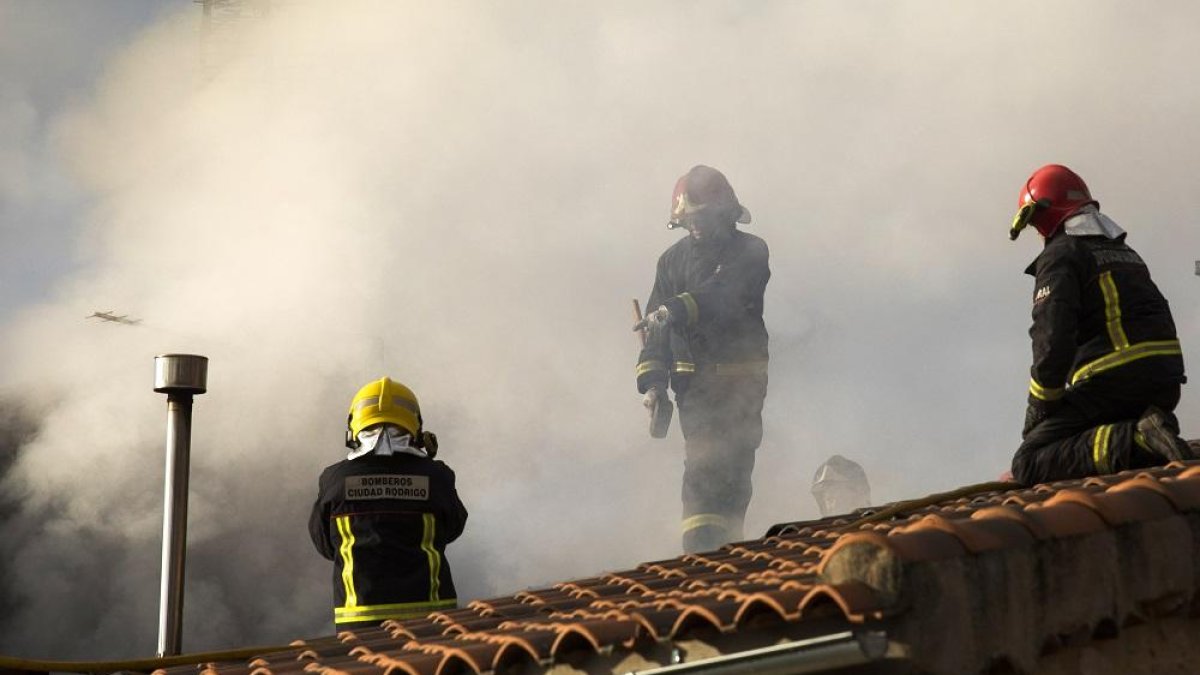 Un grupo de bomberos trabaja en el tejado de la vivienda.-ICAL