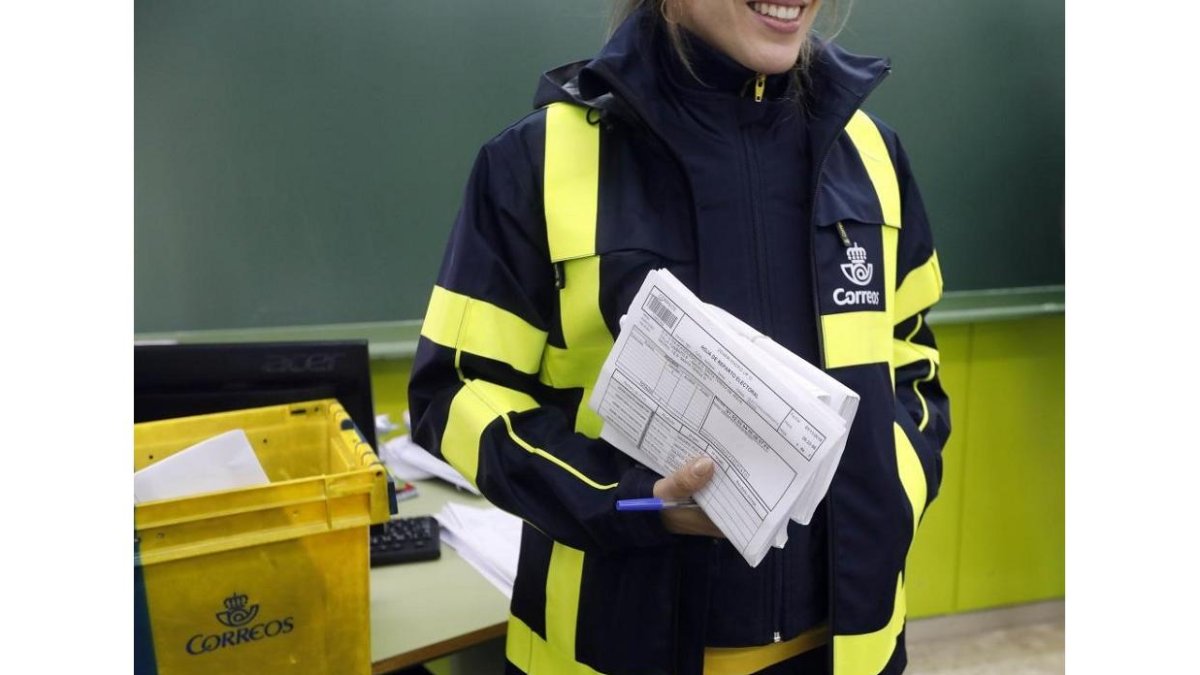 La cartero lleva el voto por correo a la mesa electoral.- E.M.