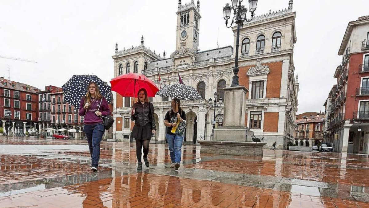 Tres mujeres caminan bajo sus paraguas ayer en la Plaza Mayor de Valladolid .-M.A.S