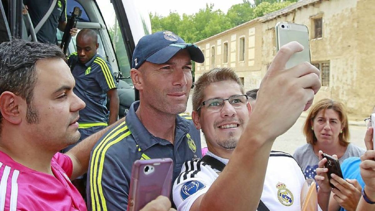 Dos aficionados del Real Madrid se hacen un ‘selfie’ con el técnico del Real Madrid B, Zinedine Zidane, justo a su llegada a Medina de Rioseco.-J. M. Lostau