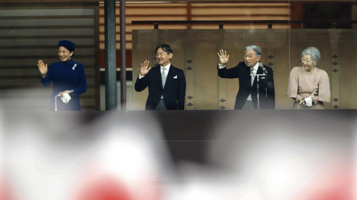 Emperor Akihito waves to national flag-waving well-wishers with Empress Michiko, Crown Prince Naruhito and Crown Princess Masako after delivering his speech marking his 85th birthday his last birthday on the throne at the Imperial Palace in Tokyo-KIMIMASA MAYAMA / EPA
