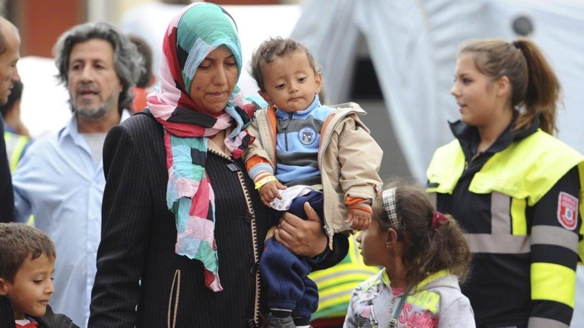 Una mujer y un niño, junto con otros migrantes y refugiados, son trasladados a un tren con destino a otra ciudad alemana poco después de su llegada a Múnich.-AP