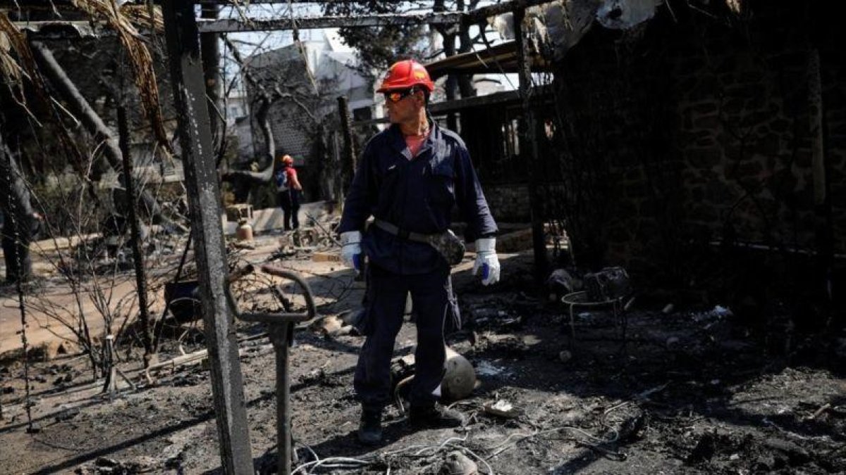 Un bombero inspecciona una de las viviendas quemadas por las llamas en la ciudad de Mati, próxima a Atenas.-ALKIS KONSTANTINIDIS (REUTERS)