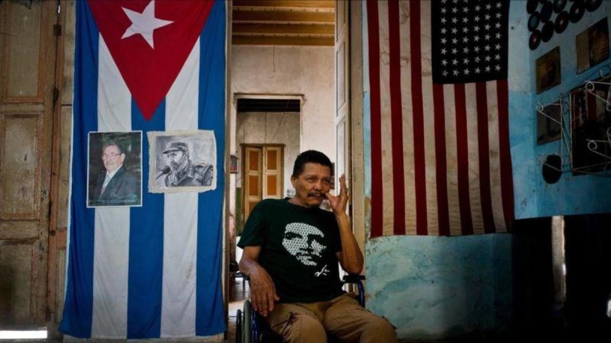 El cubano Armando Ricart Batista, actor y exboxeador, posa ante la bandera cubana y retratos de los Castro en su casa de la Habana.-RAMÓN ESPINOSA / AP