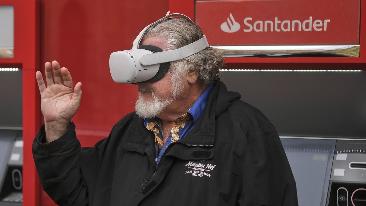 Una persona mayor utiliza unas gafas de realidad virtual en un cajero automático.-ENRIQUE CARRASCAL.