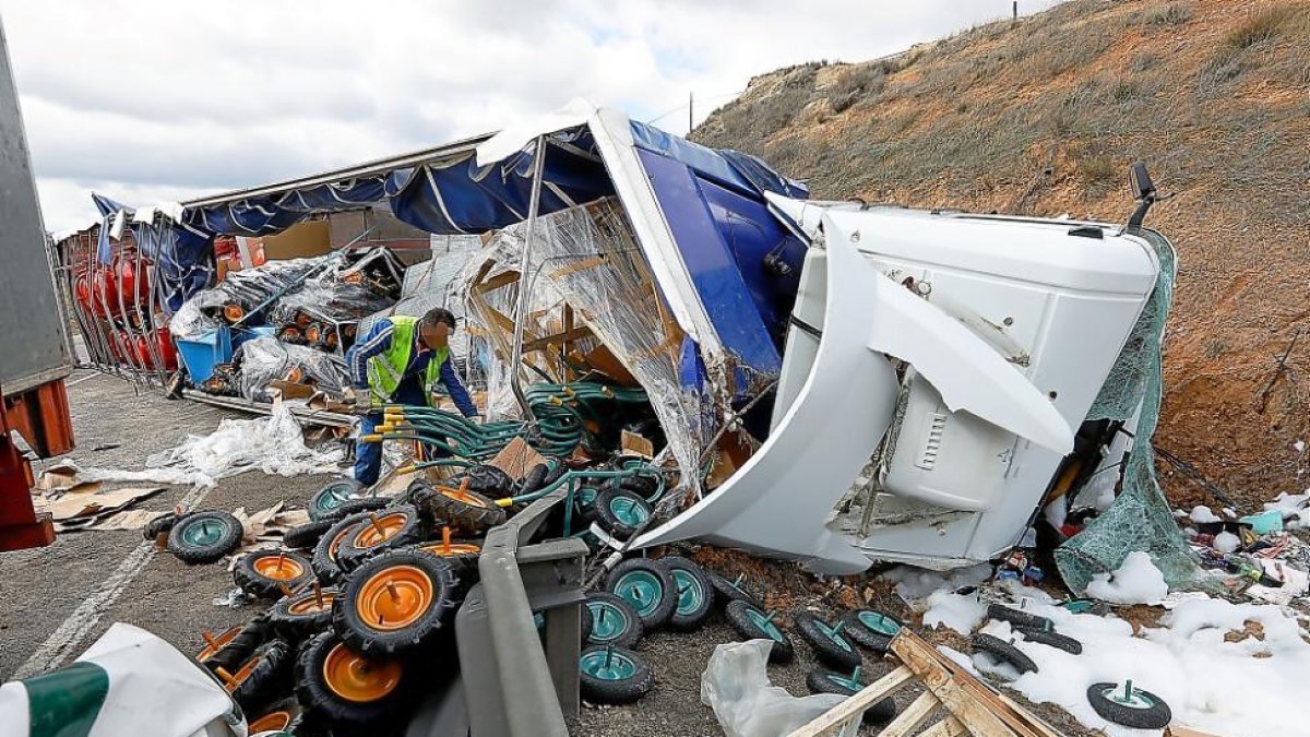 Un operario trabaja en el trasbase de la carga del camión volcado sobre la calzada de la N-122 en Peñafiel ayer, que tardó 8 horas en ser desalojado.-J. M. LOSTAU