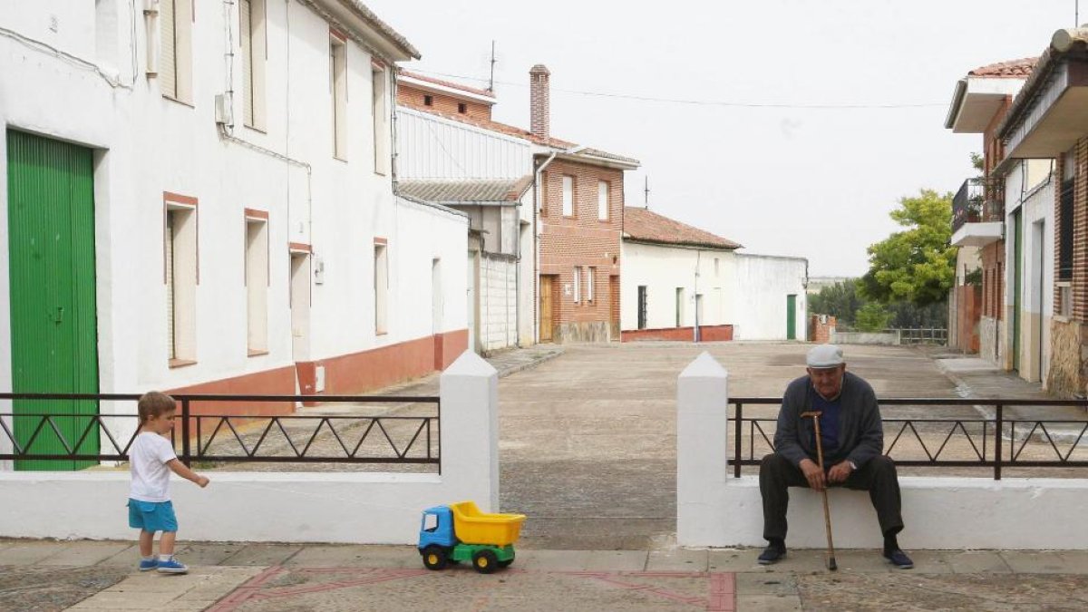 Un pequeño juega junto a una persona mayor en la localidad vallisoletana de Mayorga.-ICAL