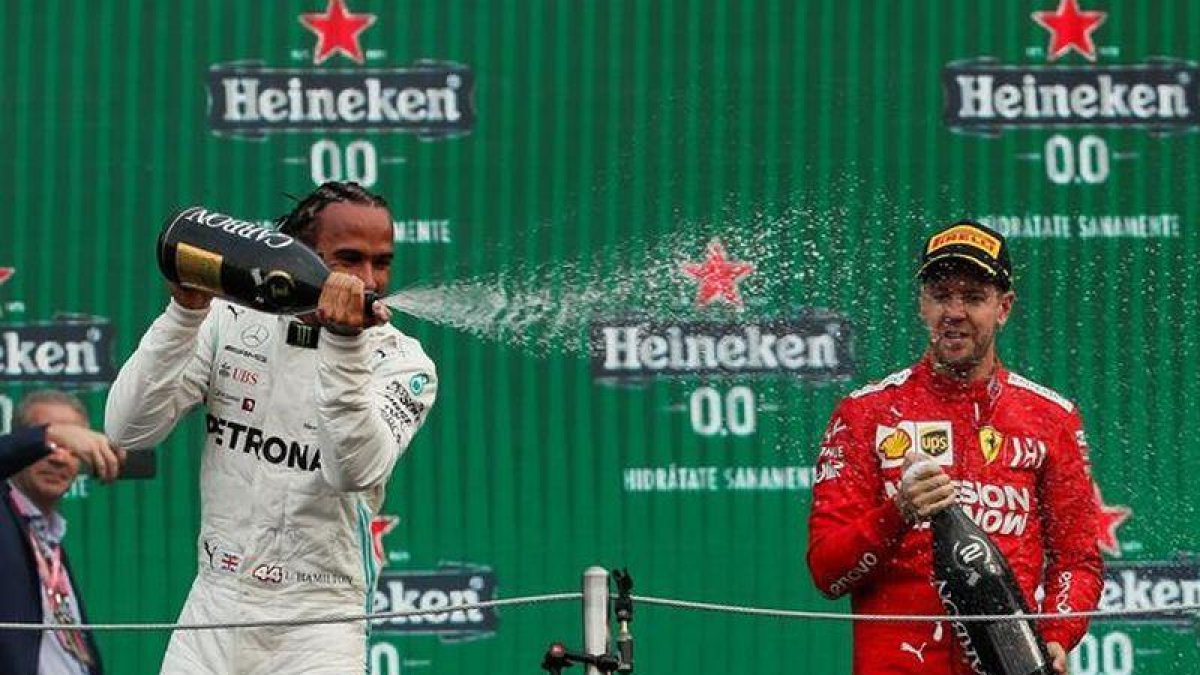 El británico Lewis Hamilton (i) de Mercedes celebra al ganar el Gran Premio de México de Fórmula Uno con el alemán Sebastian Vettel, segundo lugar, de Ferrari este domingo en el Autódromo Hermanos Rodríguez, en Ciudad de México.-EFE / José Méndez