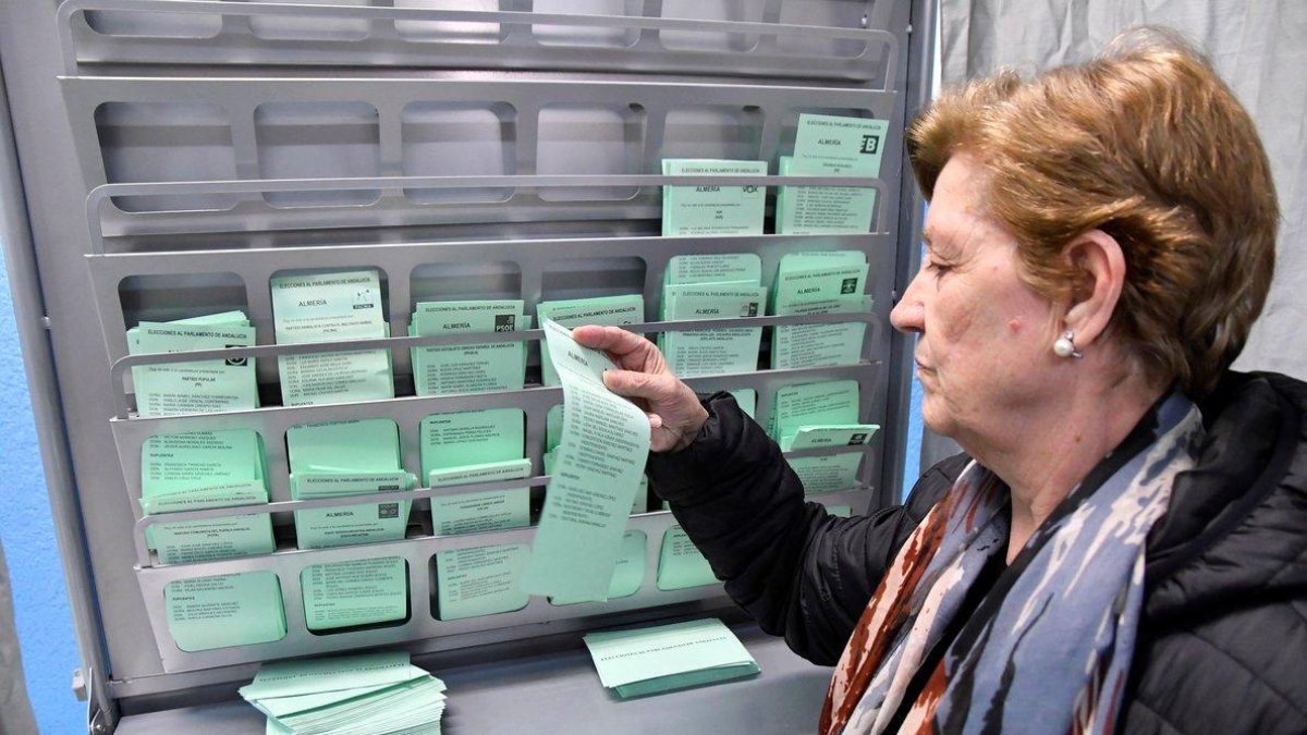 Una mujer elige una papeleta en las un colegio electoral de Almería.-EFE / CARLOS BARBA