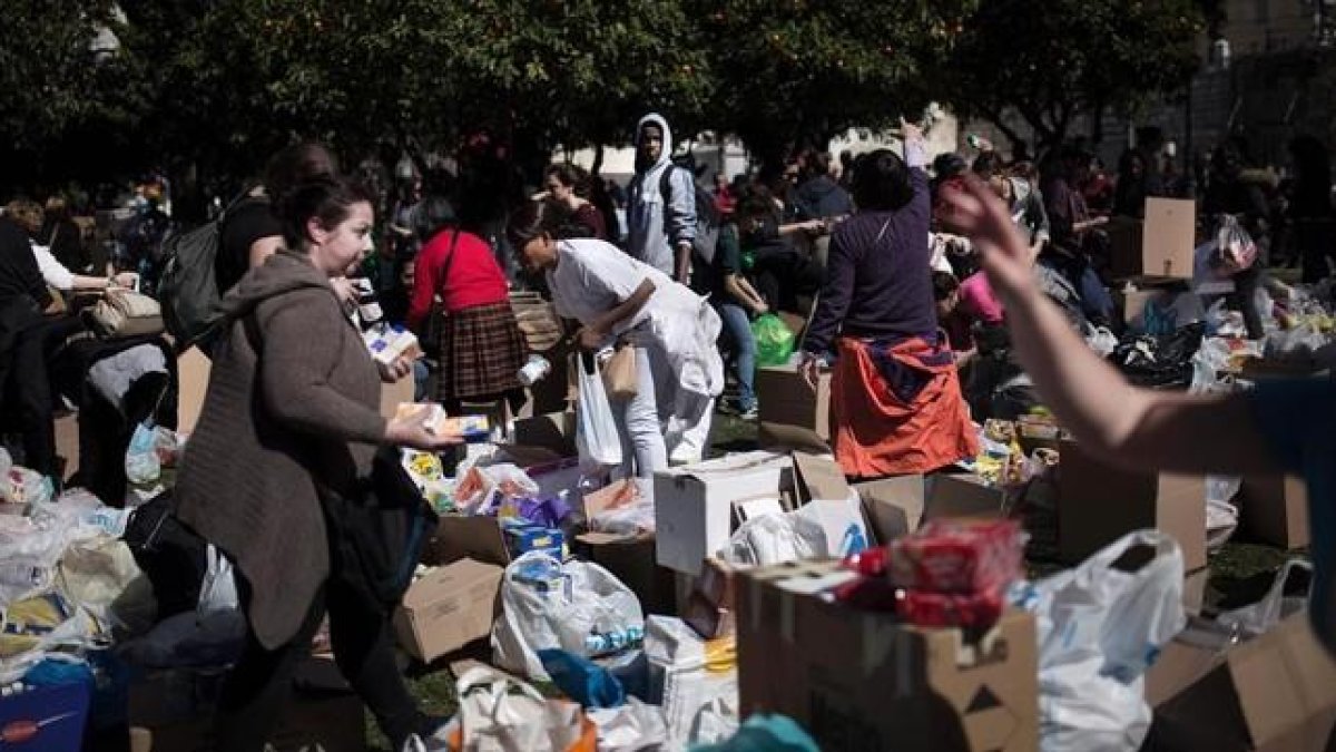 Un grupo de voluntarios reúne las bolsas y cajas que han traído vecinos de Atenas para los refugiados.-AFP / ANGELOS TZORTZINIS