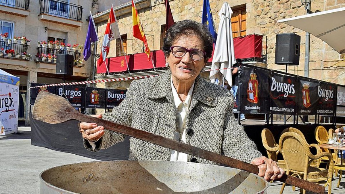 La cocinera arandina Sery Bermejo, junto a un guiso tradicional, en la Plaza Mayor de Salas de los Infantes, donde hace unos días recibió un homenaje junto a otras veteranas cocineras que han hecho historia en la cocina de la provincia de Burgos.-ARGICOMUNICACIÓN