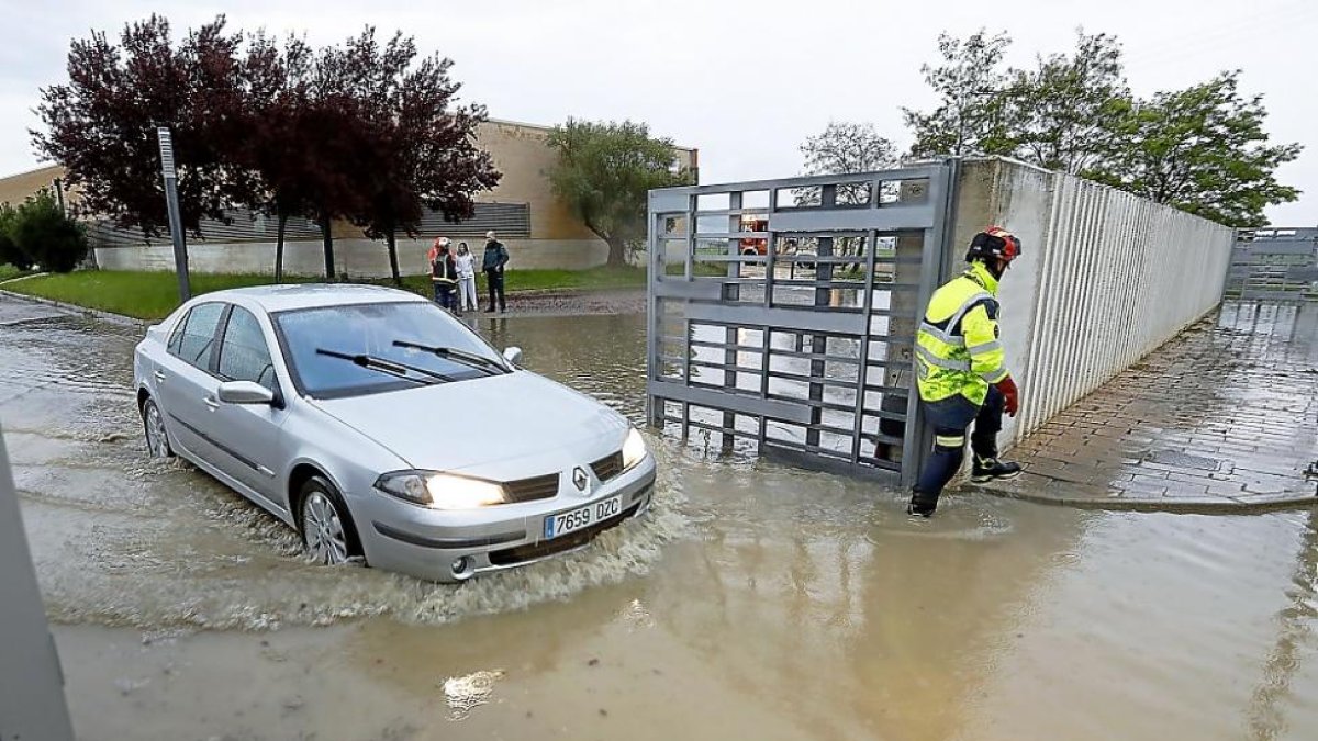 Un coche sale del centro de salud de Renedo por una vía inundada después de la tormenta.-J.M. LOSTAU