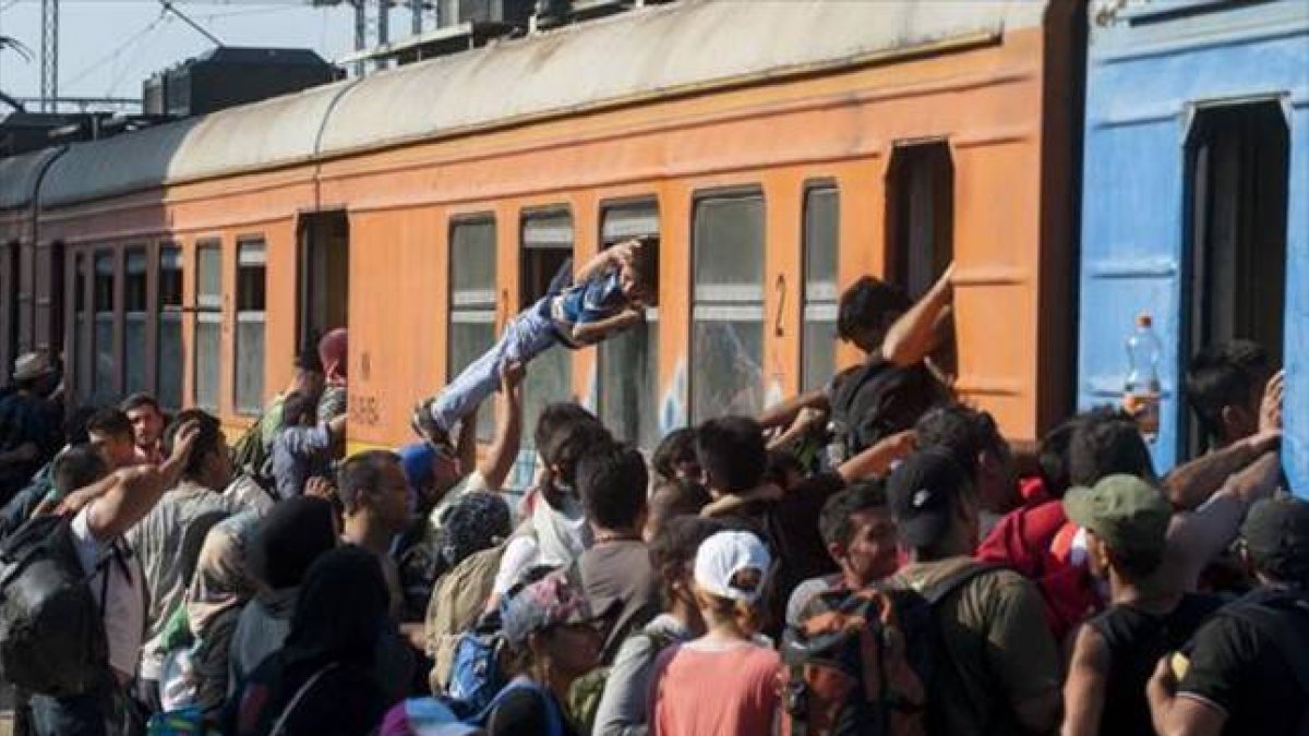 Decenas de inmigrantes y refugiados intentan subir a un tren en una estación de Macedonia con destino a Serbia, el martes.-