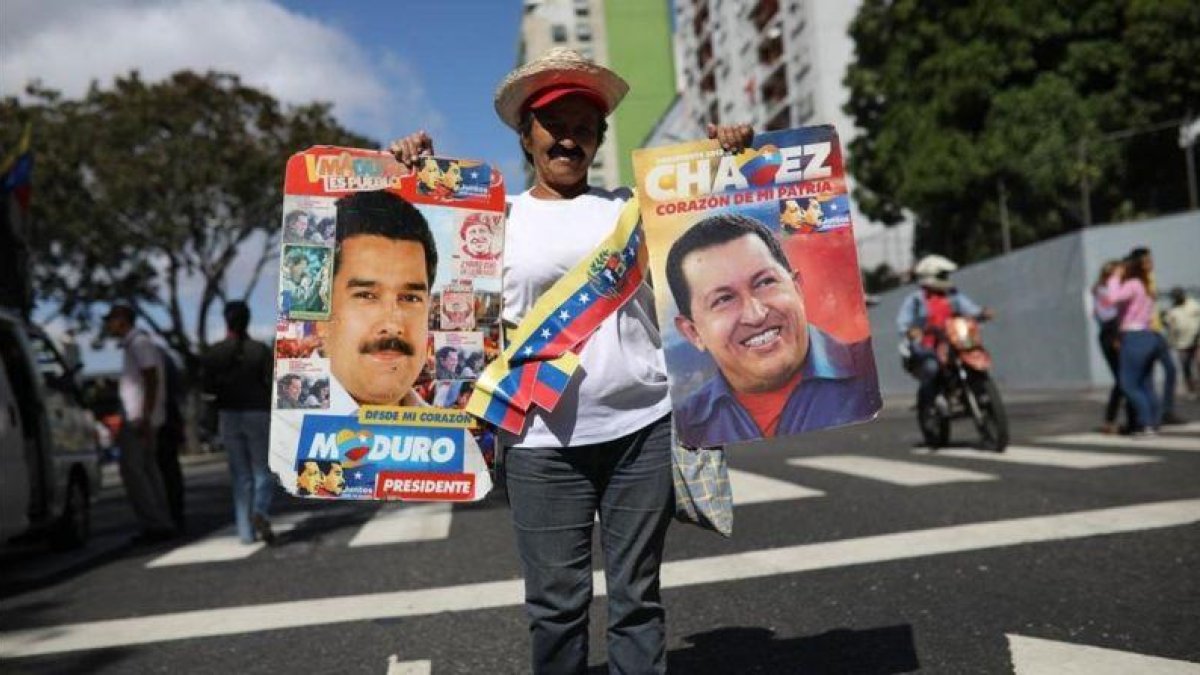 Una simpatizante de Maduro sostiene un cartel del mandatario y otro de Hugo Chávez en una manifestación en Caracas.-RODRIGO ABD (AP)