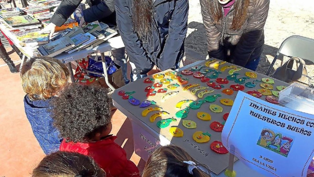 Varios alumnos del CRALa Villa observan los imanes de uno de los puestos del mercadillo.-EL MUNDO