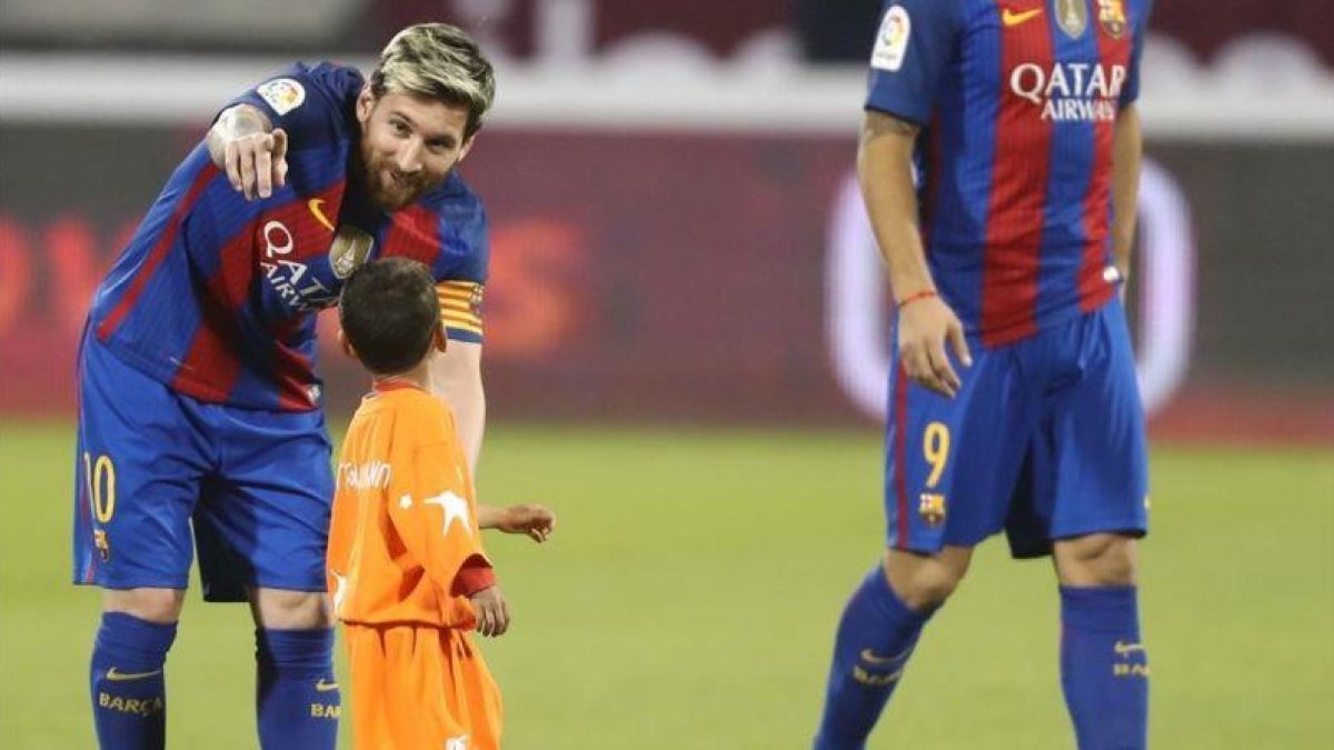 Messi indica a Murtaza, el niño afgano, que debe abandonar el césped en Doha.-AFP / KARIM JAAFAR