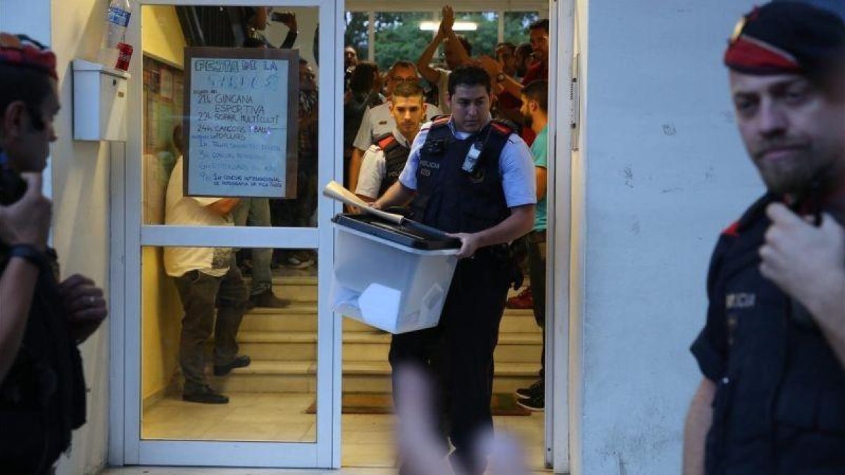 Un mosso se lleva una urna de un colegio durante el referéndum del 1-O.-RICARD CUGAT