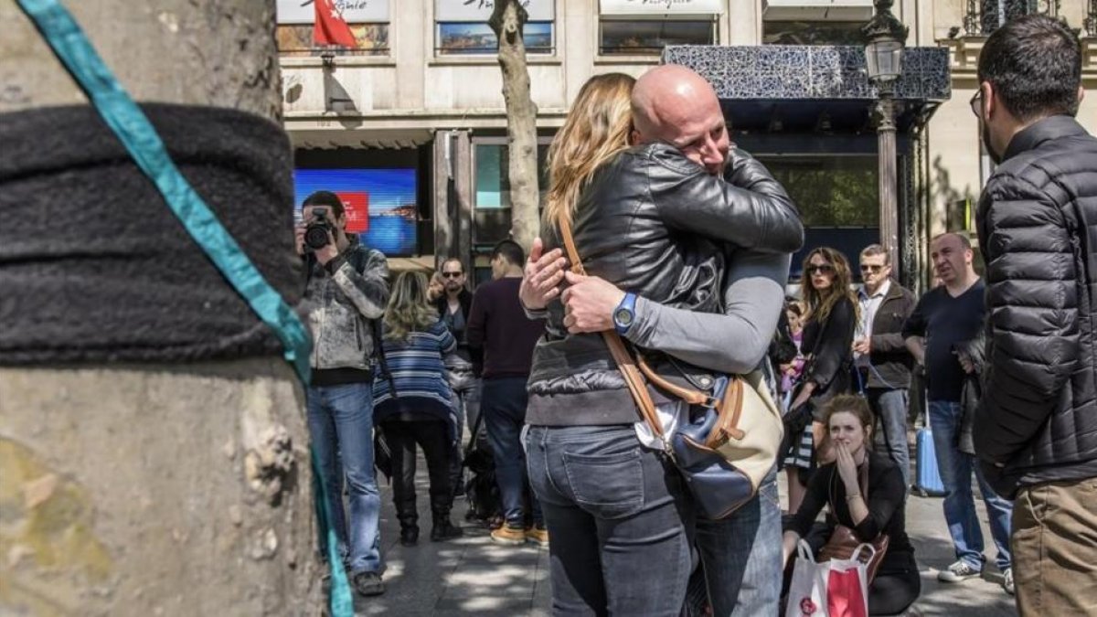 Varias personas lloran tras depositar flores en el lugar en el que fue asesinado un policia durante un ataque yihadista perpetrado en la avenida de los Campos Eliseos de París.-EFE / CHRISTOPHE PETIT TESSON