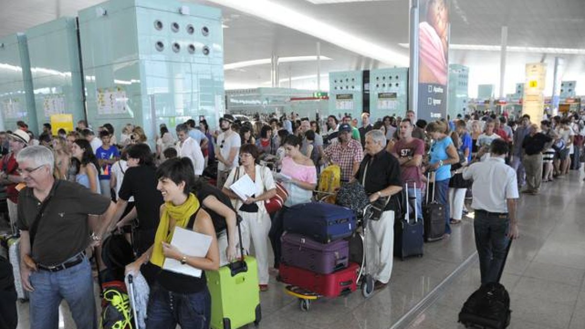 Pasajeros hacen cola para facturar las maletas que no pueden embarcar como equipaje de mano, en el aeropuerto de El Prat.-Foto: DAVID NOGUERA